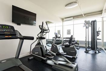 a gym with cardio equipment and a flat screen tv